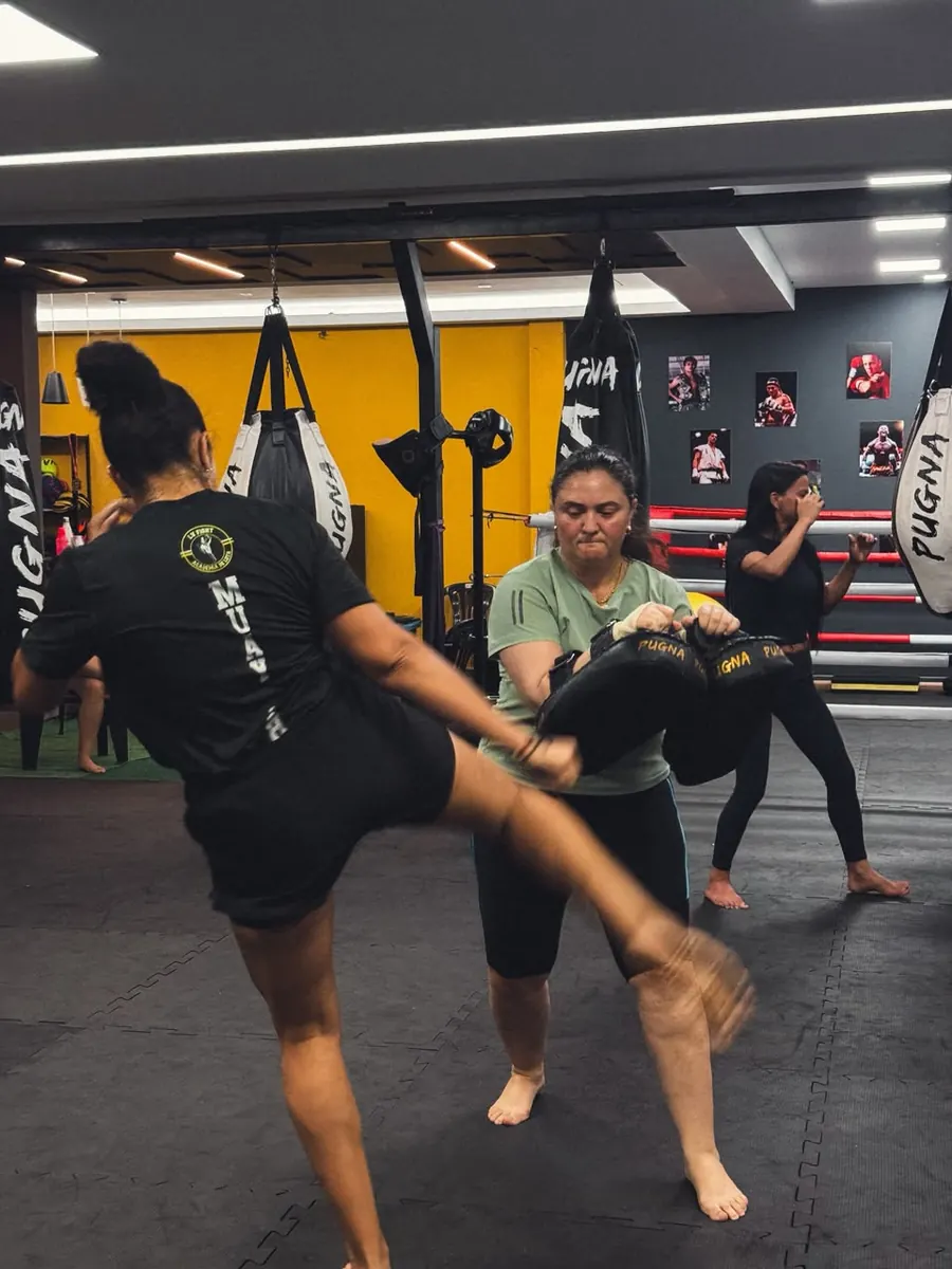 Aluna aplicando chute em aparador durante a aula